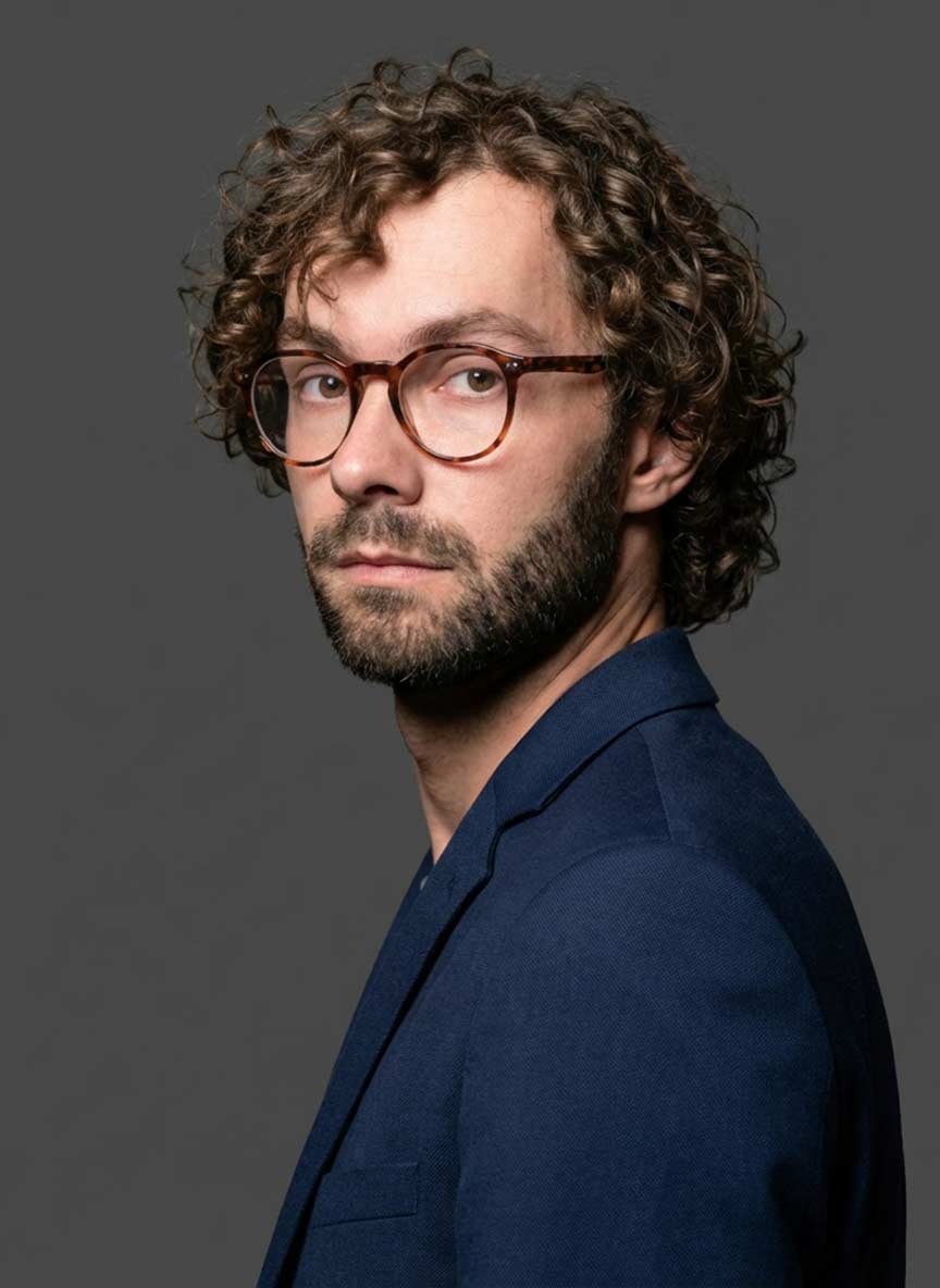 AI headshot — man with curly hair and glasses, navy blazer
